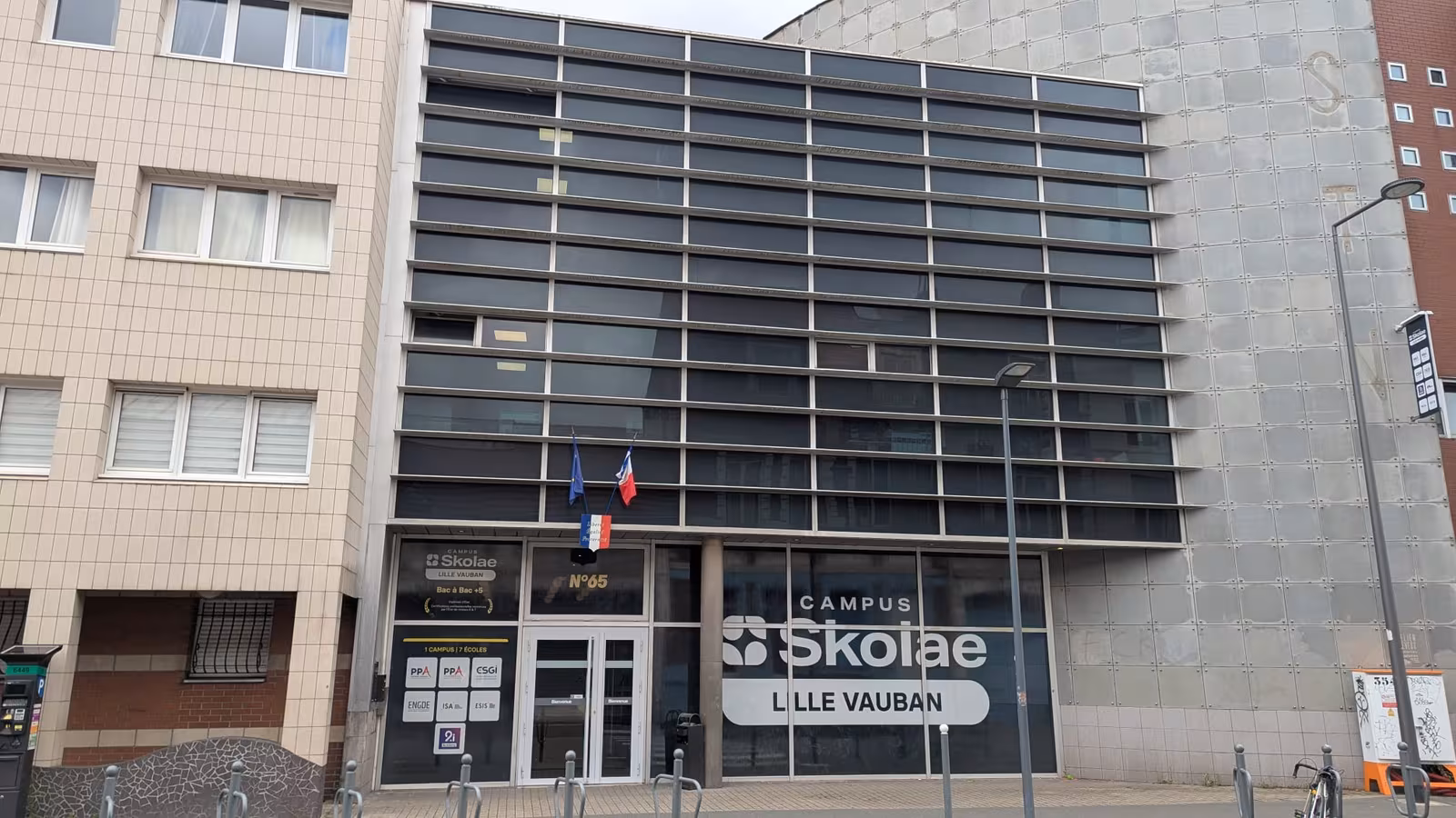 Façade vitrée d'un campus à Lille habillée en film opaque, avec le nom de l'établissement en lettrage clair