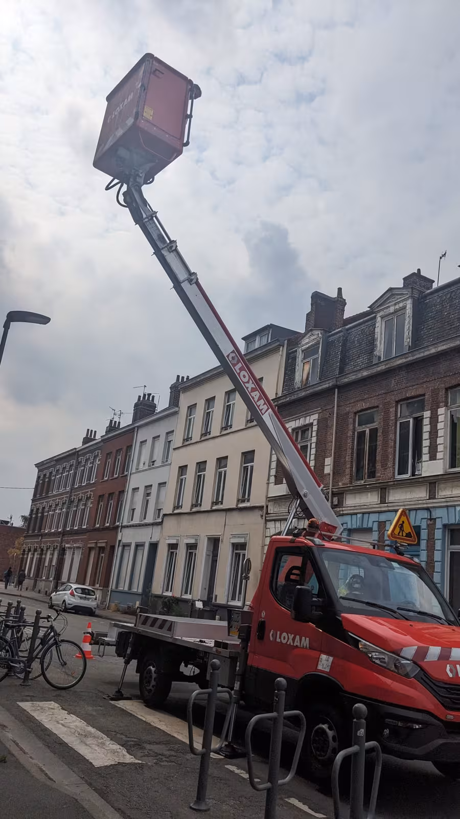 Nacelle élévatrice déployée devant la façade pour atteindre les bandeaux vitrés des étages.
